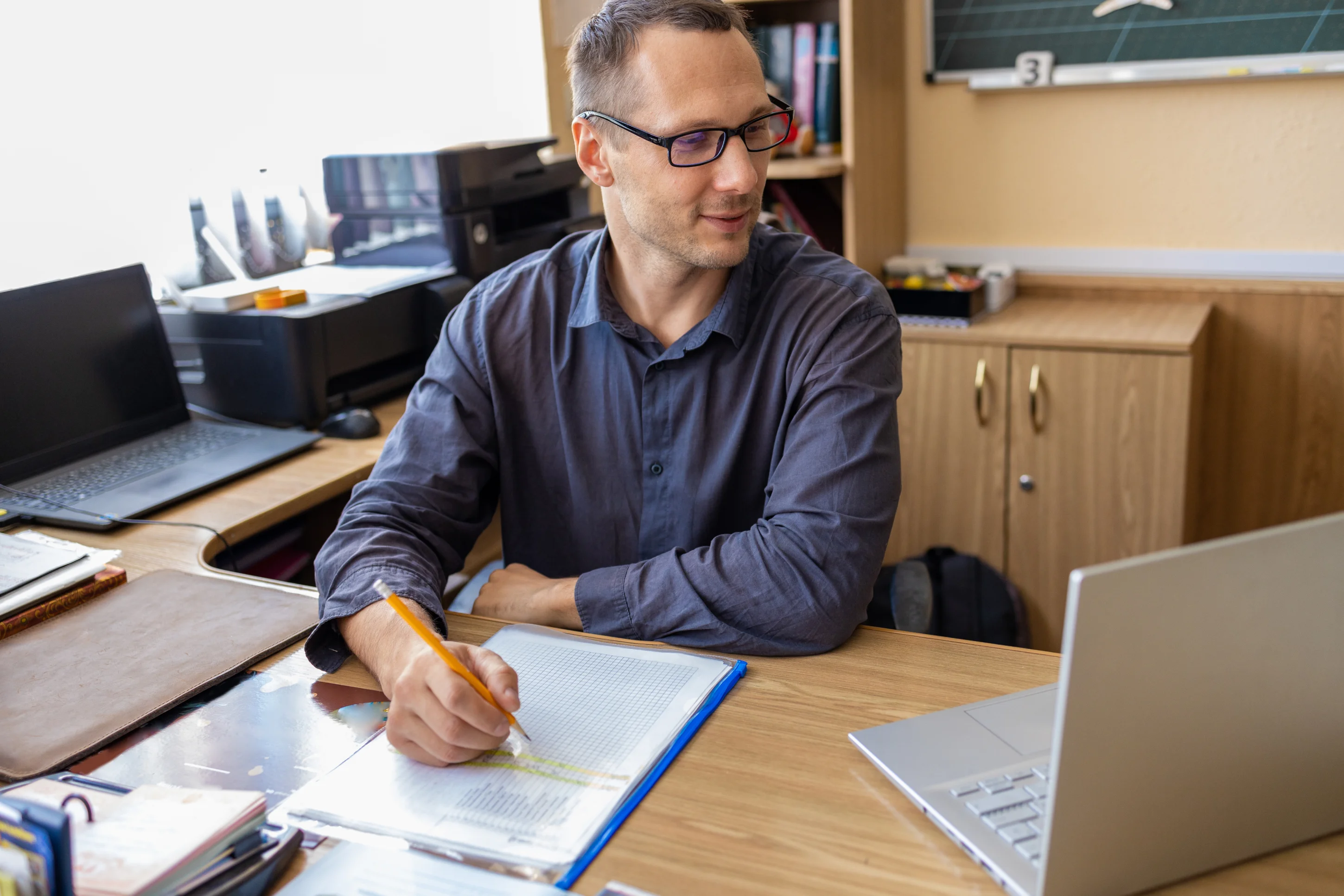 teacher writing teacher comments on students' progress report